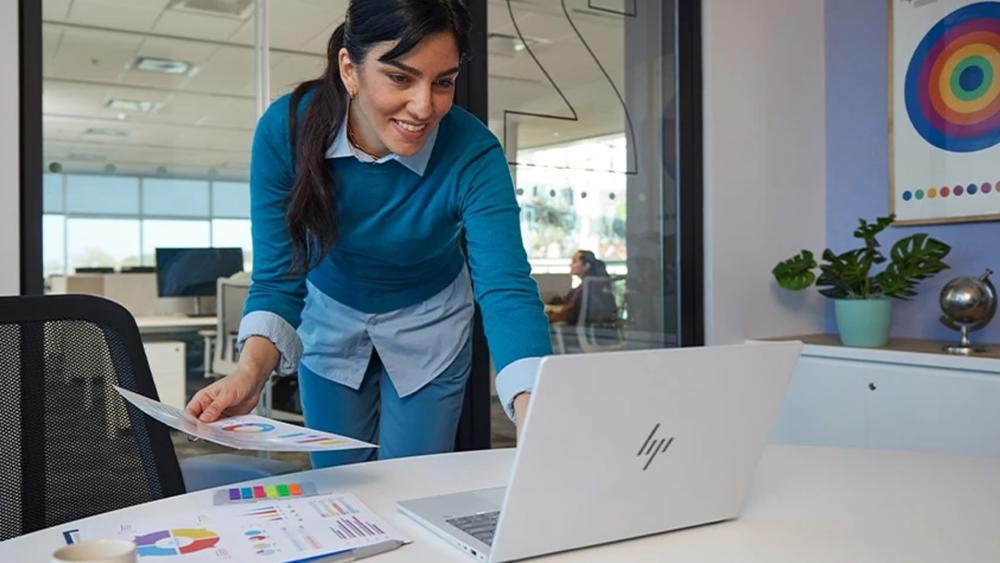 Woman reviewing charts while working on HP laptop in office