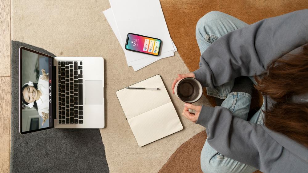 Student studying at home during an online class with laptop and notes.