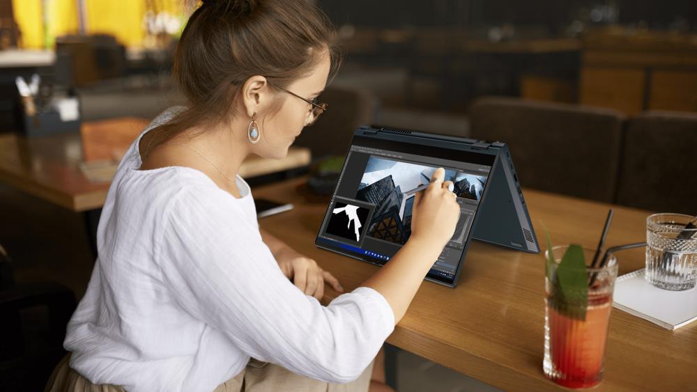 Person using an ASUS 2-in-1 laptop with stylus pen for creative design work in a café setting