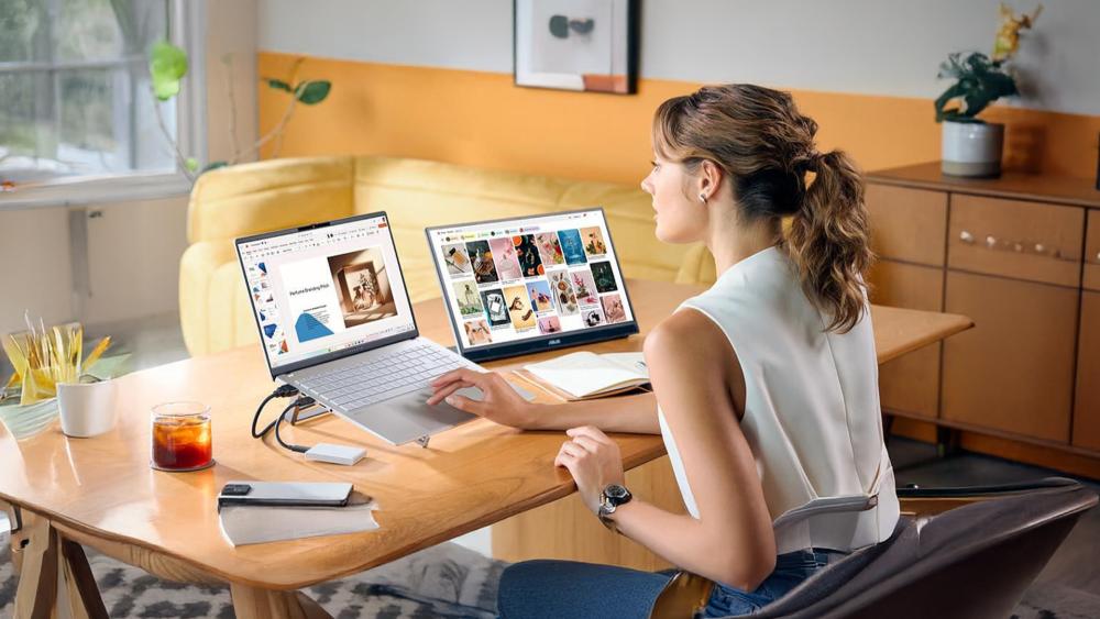 Person working at a desk using an ASUS laptop connected to a second monitor, with design and presentation content displayed on both screens.
