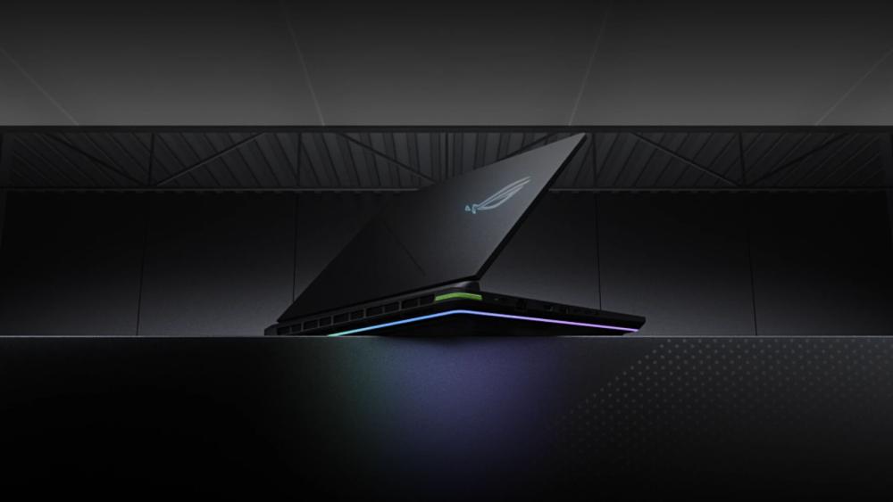 Rear view of an ASUS ROG gaming laptop with illuminated logo and RGB lighting strip on a dark background.