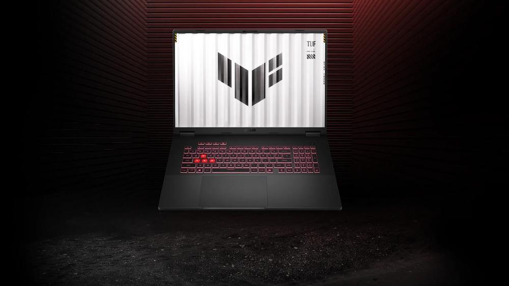 ASUS TUF gaming laptop with red backlit keyboard and TUF logo displayed on the screen against a dark background.