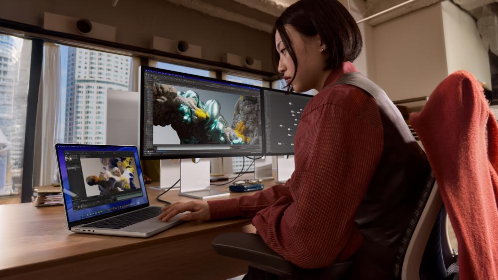 Creator editing content using MacBook and Studio Display