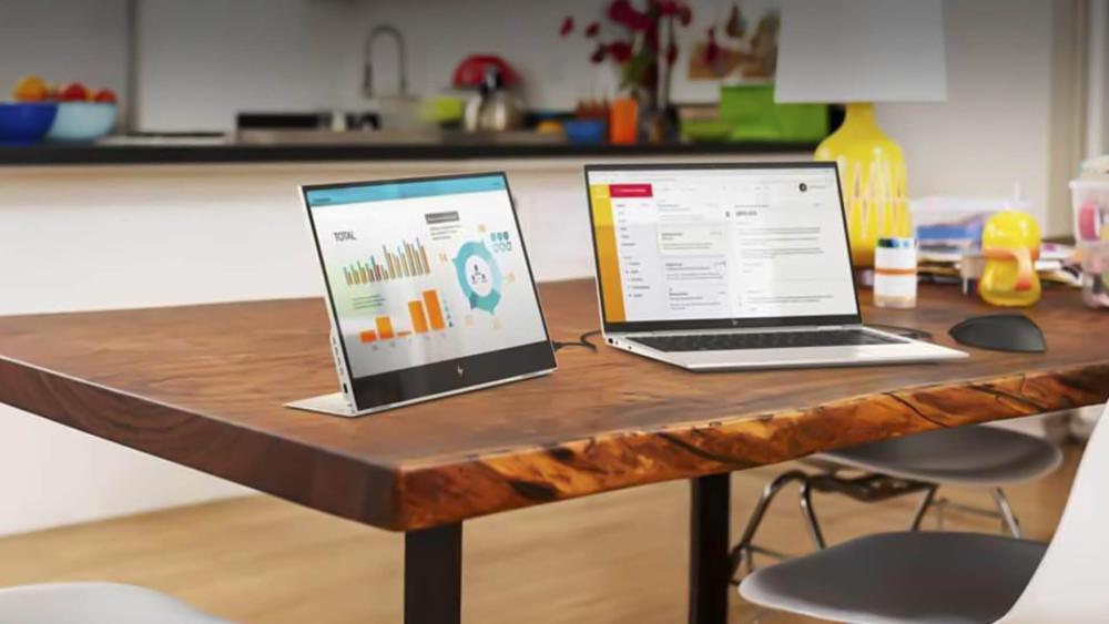Dual-screen laptop setup on a home office desk showing productivity dashboards and multitasking workspace