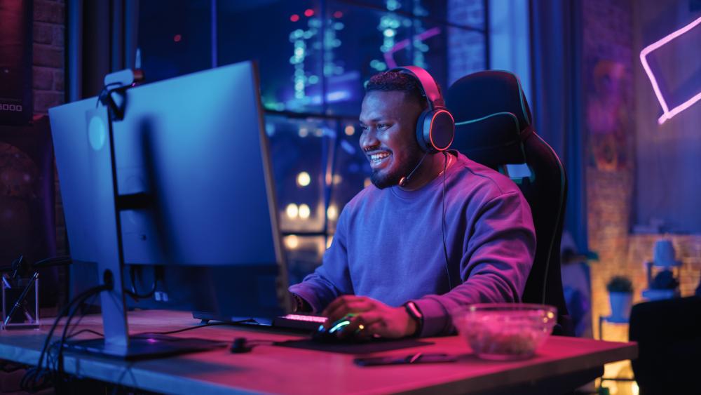 Gamer smiling at RGB PC setup during gameplay