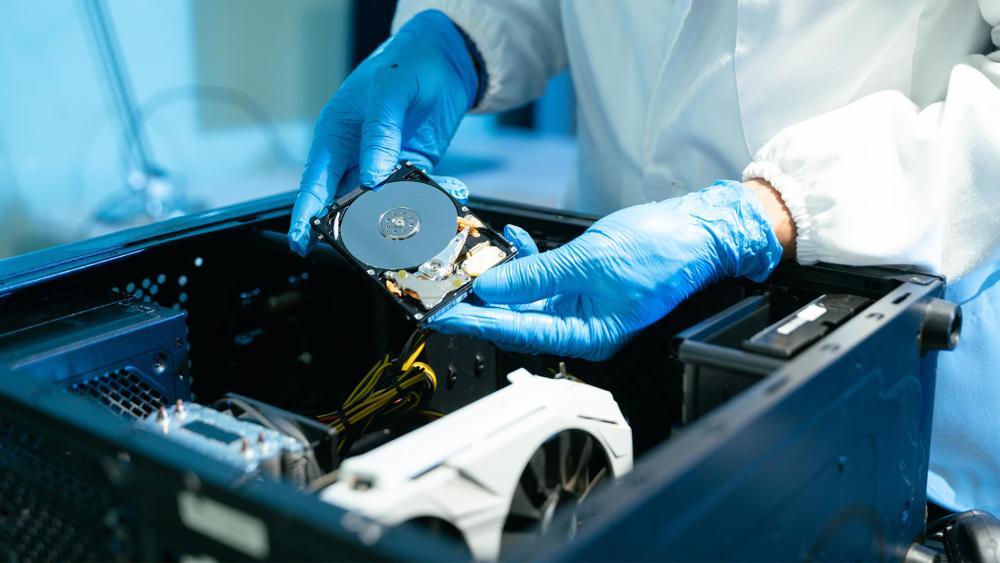 Technician installing a hard disk drive inside a desktop PC case during a storage upgrade or repair