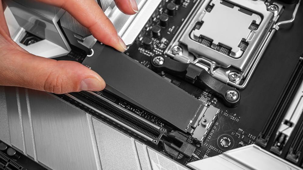 Close-up of installing an NVMe SSD into an M.2 slot on a motherboard during a PC upgrade or build.