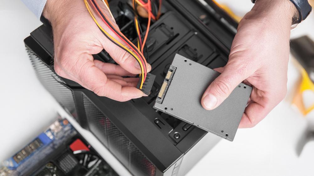 A photo of a person connecting a SATA SSD, next to a tidy workstation