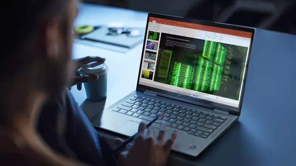 Person using a Lenovo laptop to work on a business presentation with data visualisation and slides on screen