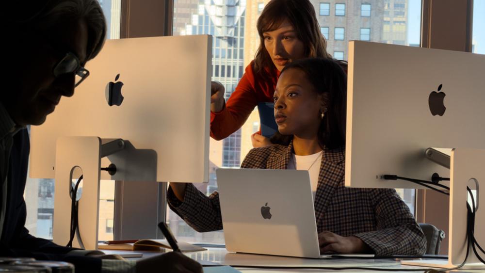 People using MacBook Air with dual monitors in office setting