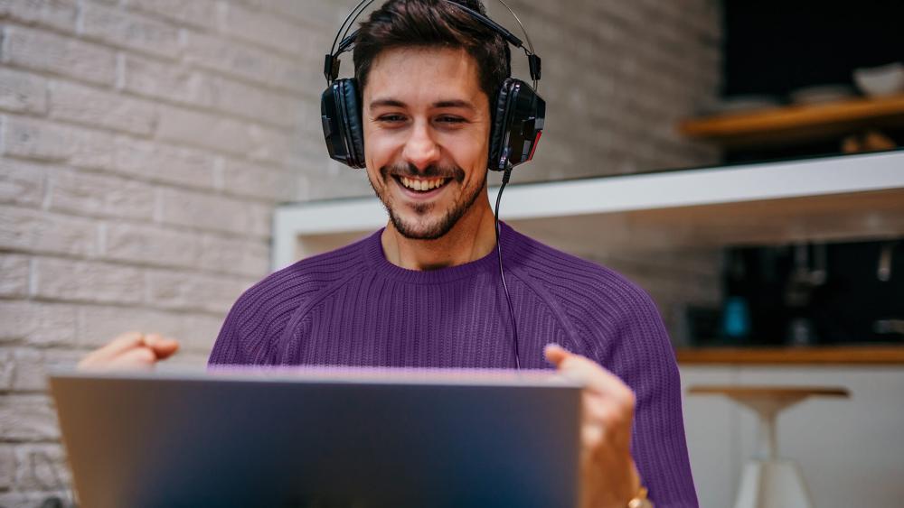 Man wearing headphones gaming on a laptop while exploring Box tech choices