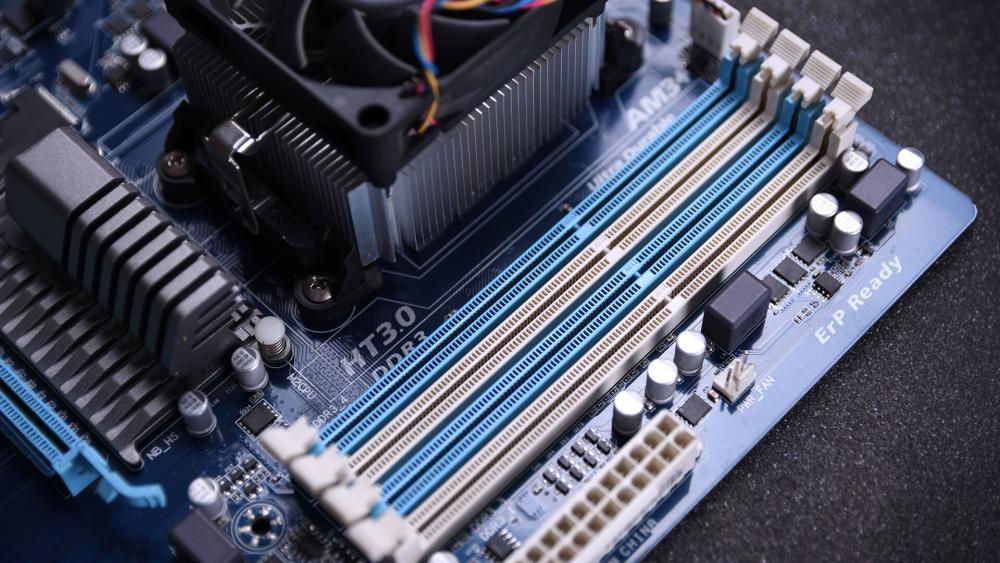 Close-up of motherboard showing RAM slots and CPU cooler installed for desktop PC memory upgrade and hardware setup.
