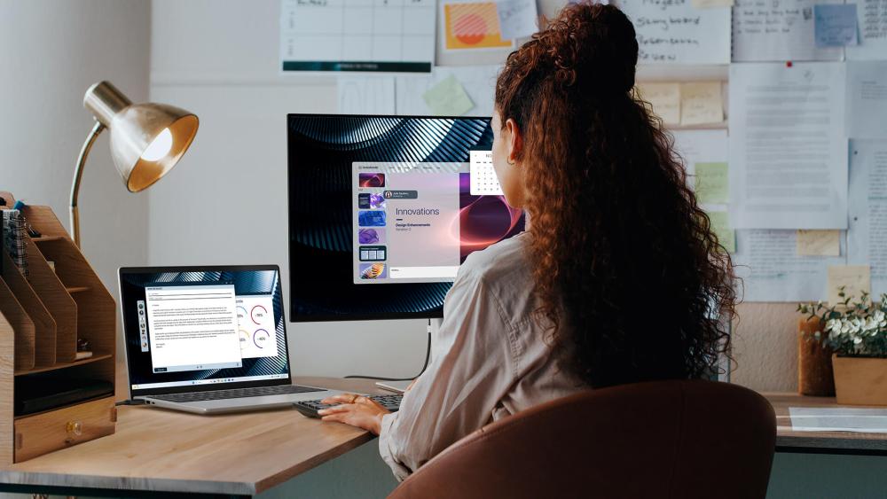 Office worker using a laptop with external monitor in a business workspace
