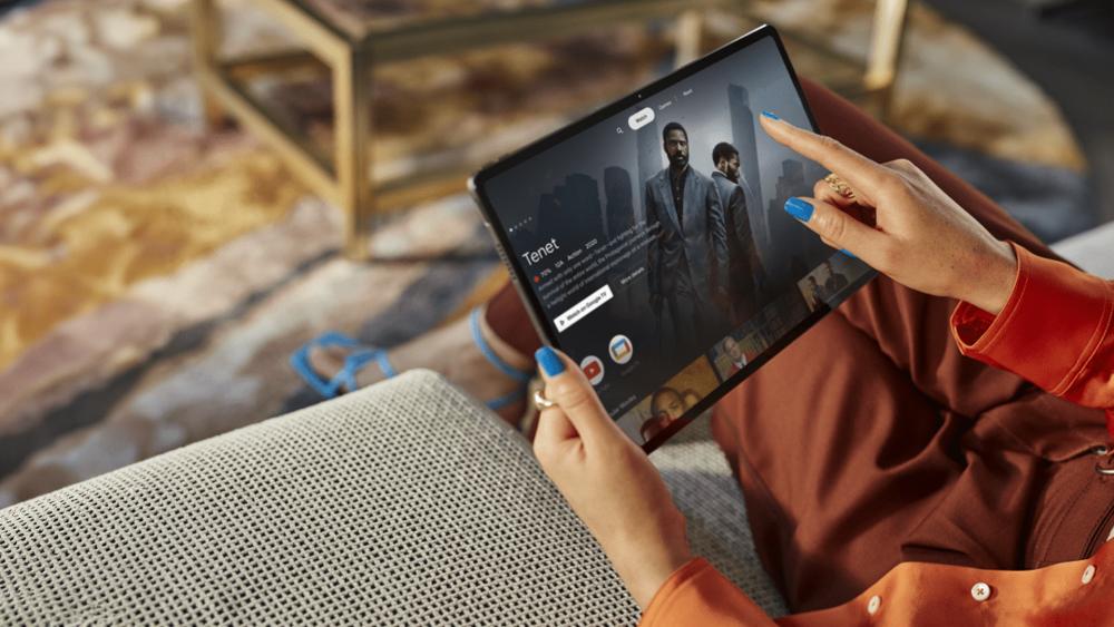 Person streaming a movie on a tablet while relaxing at home on a sofa.
