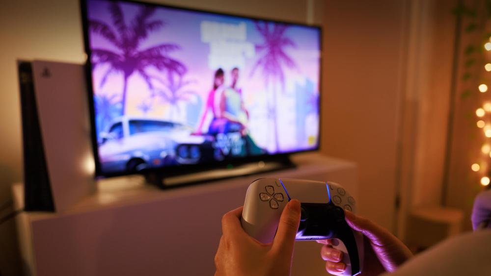 Relaxed living room gaming scene with PlayStation 5, controllers and a monitor.