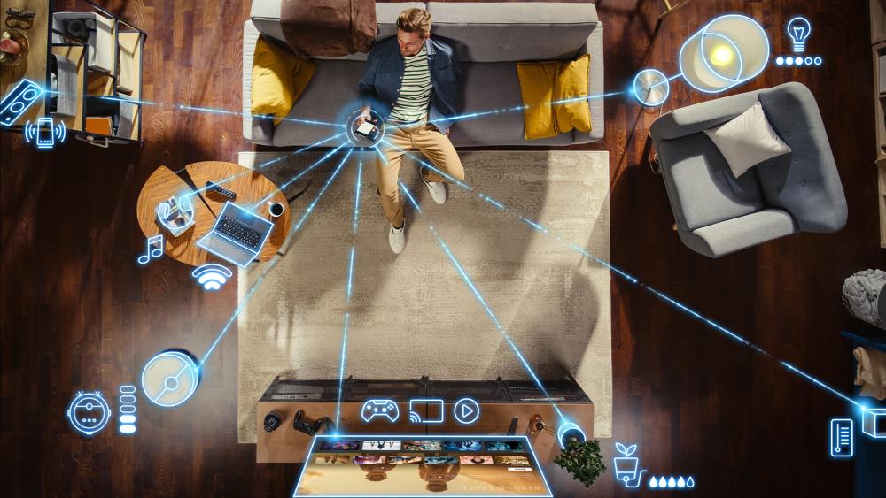 Man using smartphone connected to smart home and laptop via Wi-Fi