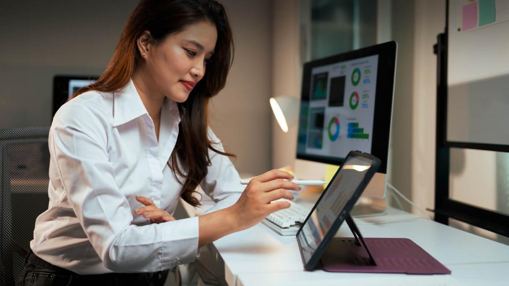 Woman using a tablet with stylus for work at a desk